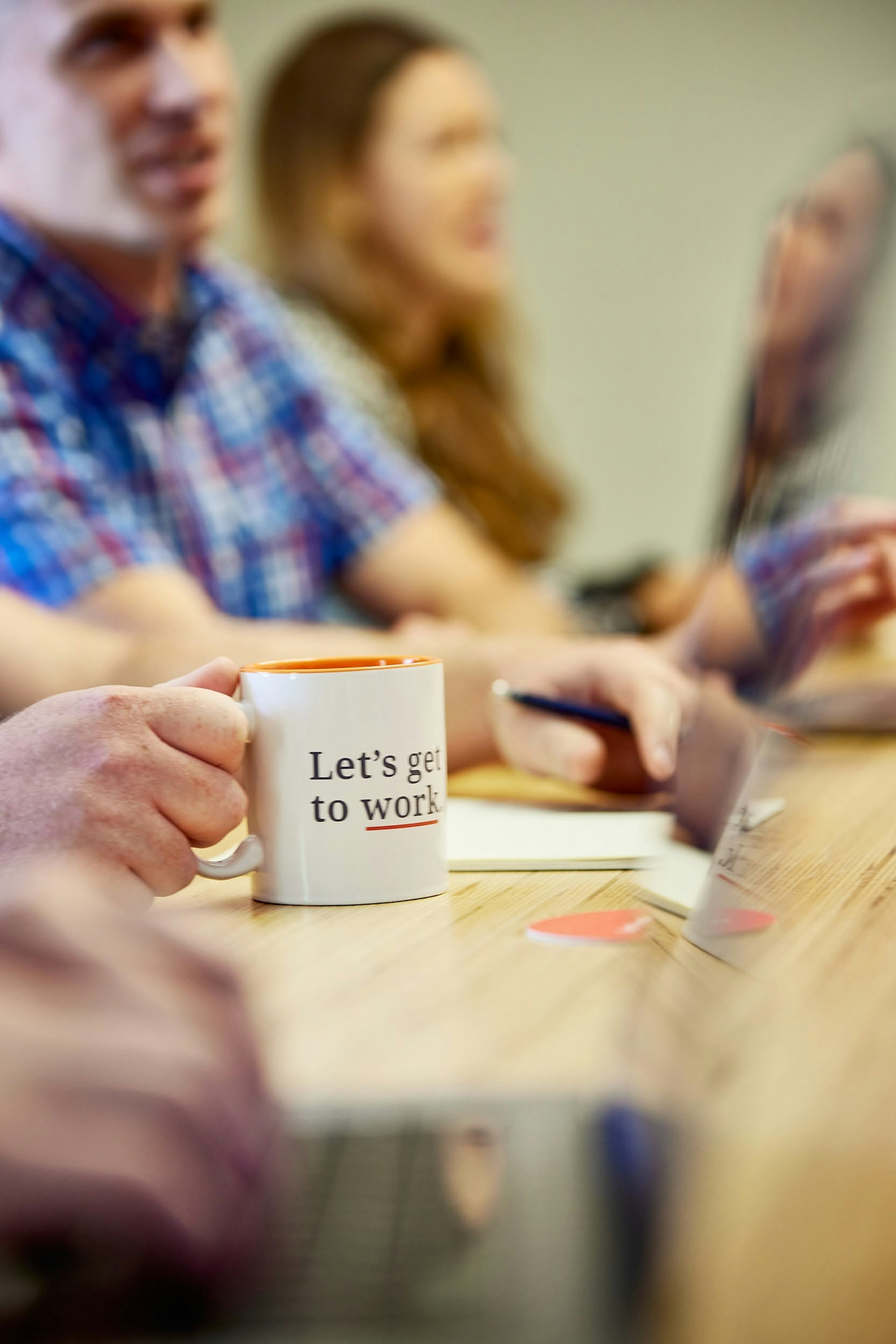 Coffee mug on a desk that says “Let's get to work.”
