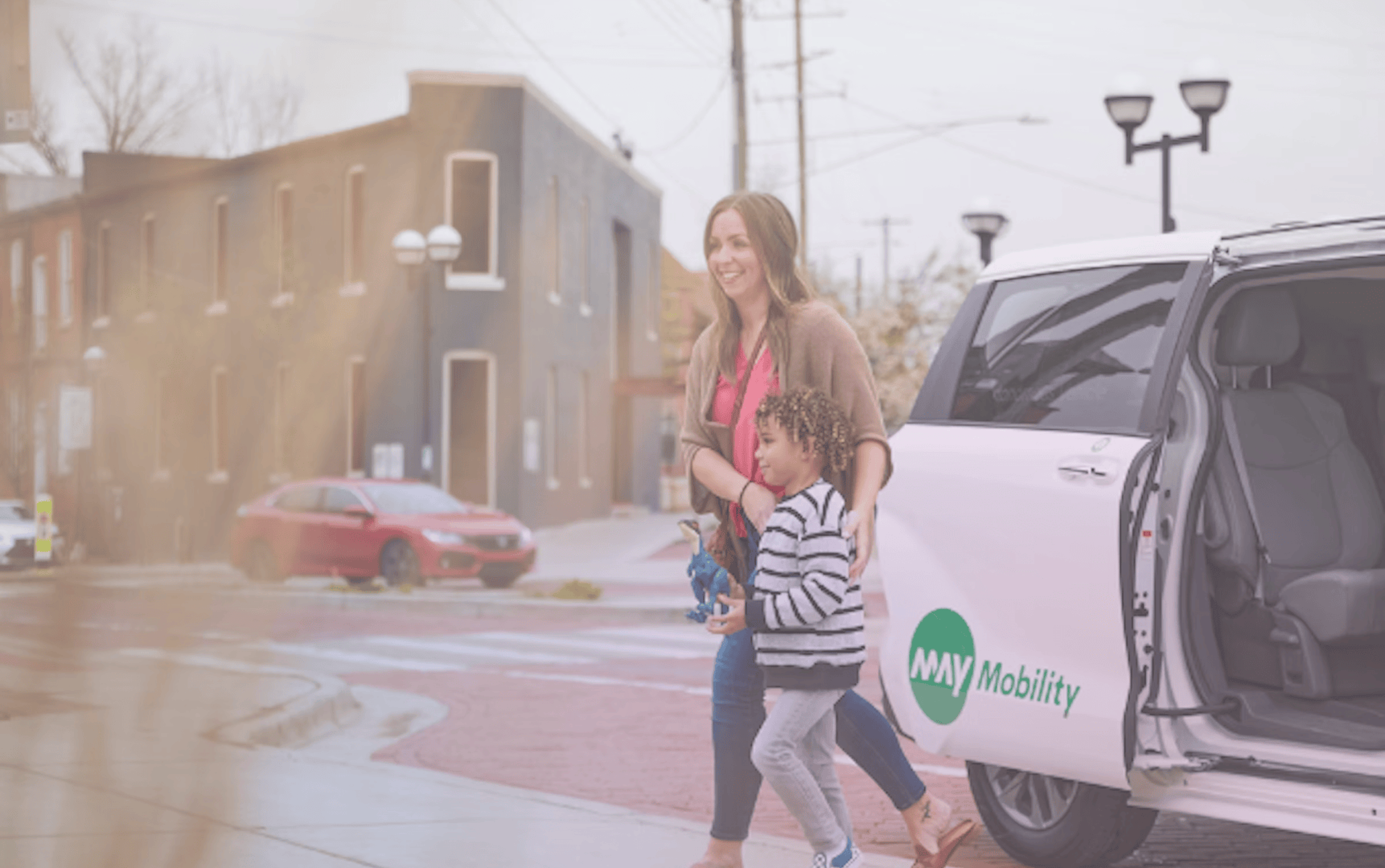 May Mobility website homepage displayed on a laptop screen, showcasing their autonomous vehicle technology with a modern, clean design featuring their signature green branding and imagery of their self-driving shuttle.